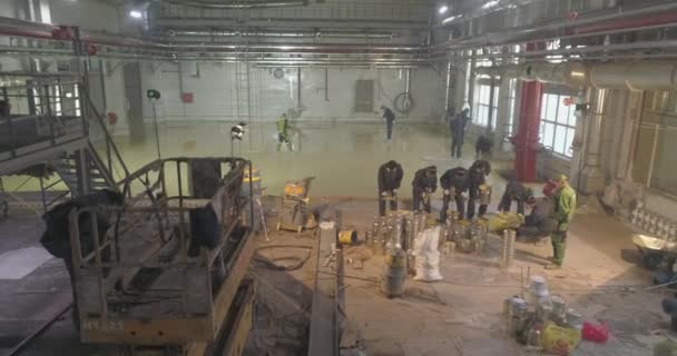 Los trabajadores hacen el piso en el taller de la planta. Trabajadores en la obra. Construcción de un nuevo taller en la planta — Vídeos de Stock