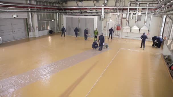 Construcción de un taller en la planta. Trabajadores en una obra de construcción. El proceso de creación de un gran área de auto-nivelación piso — Vídeos de Stock