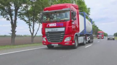 Kırmızı kamyon otoyol boyunca gidiyor. Bir grup kamyon otoyol boyunca gidiyor. Modern kamyonlar tanklarda sıvı kargo taşıyorlar
