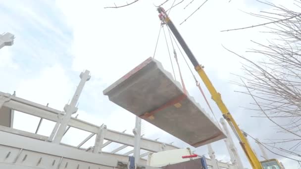 En kran lyfter en betongstege. En kran lyfter en betongplatta. Byggnadsarbeten. Trappsteg för lyftkranar — Stockvideo