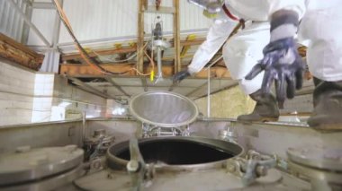 Bir işçi içeriden buharlı bir tank kamyonunun kimyasal temizliğini yapıyor. Tankerin otomatik buhar temizliği. Kimyasal koruma işçisi