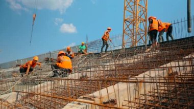 İşçiler güçlendirilmiş beton yapı yapıyorlar. Güçlendirilmiş beton. Metal bir yapıya beton dökülüyor. İnşaat alanında çalışma süreci.