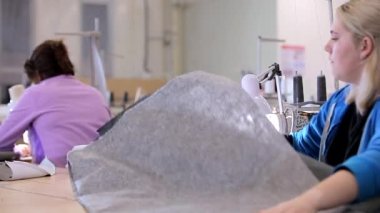 Bir terzi elbise fabrikasında çalışıyor. Tekstil üretimi. Çalışma süreci. Profesyonel ekipman dikiyorum.