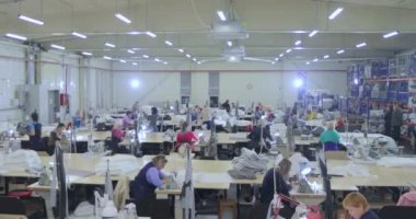 Büyük bir zaman turu üretimi. Atölyede bir sürü terzi var. Giysi fabrikasının içi. Dikiş endüstrisindeki kadınlar