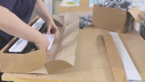 Συσκευάζοντας πλαστικά μέρη σε ένα κουτί. Ο εργαζόμενος βάζει τα εμπορεύματα σε ένα κουτί για την αποστολή στον πελάτη — Αρχείο Βίντεο