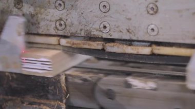Makine ahşap bloğun kenarına yapıştırıcı sürer. Mobilya fabrikasında otomatikleştirilmiş üretim hattı