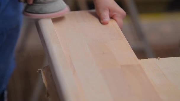 Lijado de muebles de madera. Un trabajador está lijando una pieza de madera en una fábrica de muebles. Proceso de fabricación de muebles — Vídeos de Stock