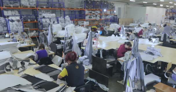 大きな縫製工房。衣類工場での作業プロセス。縫製工場では多くのストレスが働いています。シームレスは工場で製品を作る。衣服工場 — ストック動画