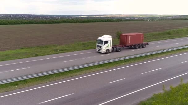 Vrachtwagen op de snelweg uitzicht vanaf de drone. Vrachtwagen rijdt op de moderne snelweg rond groen gras bovenaanzicht. Goederenvervoer. Logistiek — Stockvideo