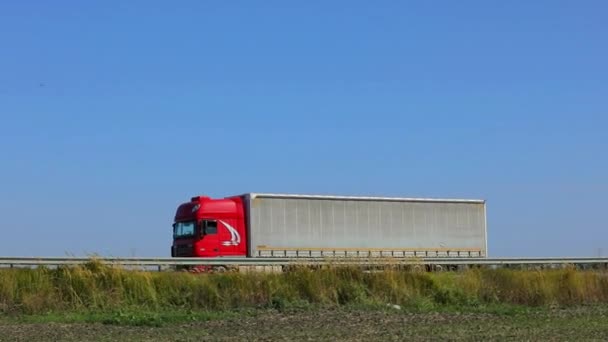 A teherautó az autópálya mentén halad napsütéses időben. A teherautó egy modern úton halad. Teherautó a pályán — Stock videók