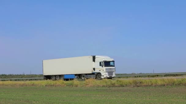 Ein weißer Wagen fährt bei sonnigem Wetter die Autobahn entlang. LKW auf der Autobahn — Stockvideo