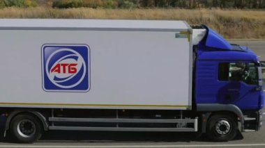 Güneşli bir günde bir kamyon otoyol boyunca gidiyor. Pistte kamyon var. Nakliye aracı. Kamyon güneşli havada otoyol boyunca sürer. Kamyon modern bir yolda ilerliyor..