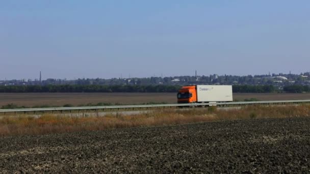 Ciężarówka jedzie wzdłuż autostrady w słoneczną pogodę. Ciężarówka jedzie nowoczesną drogą. Ciężarówka na torze — Wideo stockowe