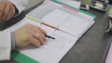 Doktor hastalara notlar alır. Doktor tıbbi geçmişini okuyor.