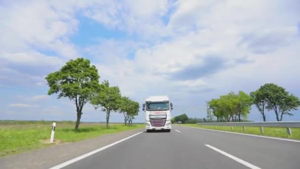 Un convoy de camiones conduce por la carretera. Camión blanco conduciendo por la carretera. Un camión con un camión cisterna conduce por la carretera en tiempo soleado. — Vídeo de stock