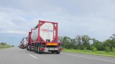 Kamyonlar yol boyunca gidiyor. Bir kamyon konvoyu otobanın altından geçiyor. Pistteki modern kamyonlar