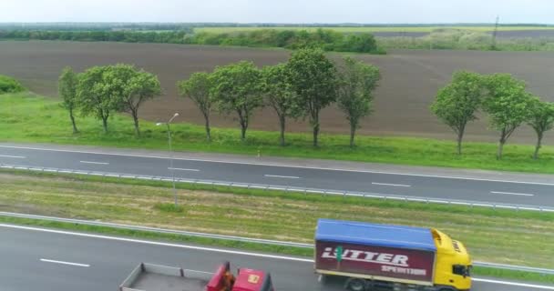 Грузовики ездят по современному шоссе вокруг зеленой травы вид сверху. Грузовик на шоссе с беспилотника. — стоковое видео