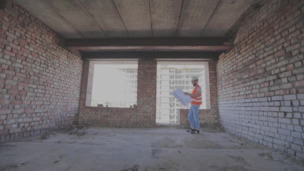 Ingenieurs met een blauwdruk in een nieuw huis. Bouwvakkers in een nieuw gebouw. — Stockvideo