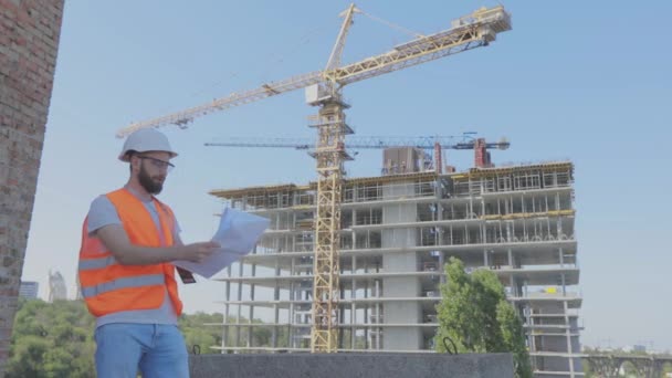 Inżynier z rysunkiem na placu budowy. Młody inżynier na budowie. Inżynier na placu budowy — Wideo stockowe