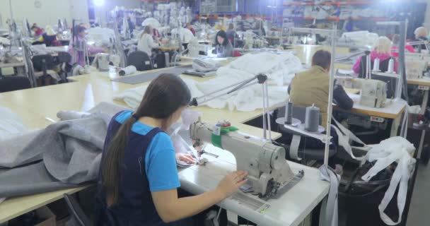 Uma mulher trabalha numa máquina de costura. Uma mulher trabalha numa fábrica de vestuário. Fazendo têxteis em uma fábrica — Vídeo de Stock