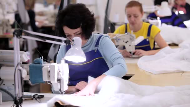 Una mujer trabaja en una fábrica de ropa. Una mujer trabaja en una máquina de coser. Fabricación de textiles en una fábrica — Vídeo de stock