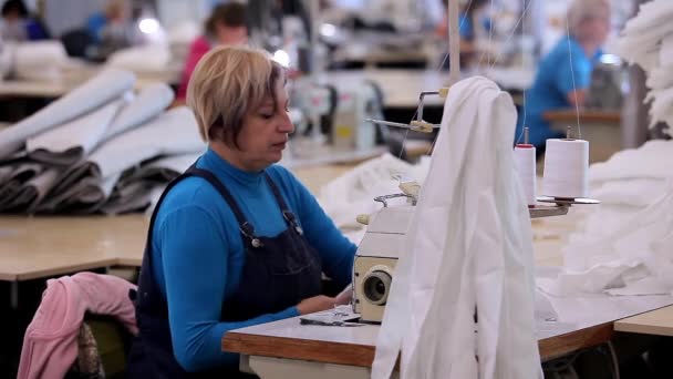 Many seamstresses work in a garment factory. Working process at a garment factory. Large sewing workshop. Seamstresses make products in a factory. Garment factory — Vídeo de Stock
