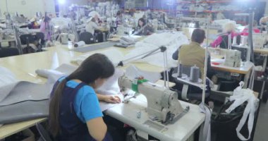 Giysi fabrikası. Birçok terzi bir giyim fabrikasında çalışır. Bir giyim fabrikasında çalışma süreci. Büyük dikiş atölyesi. Terziler fabrikada ürün yaparlar.. .