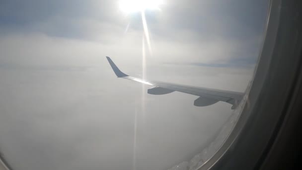 飛行機の窓から雲。飛行機の窓からの乗客の眺め。飛行機の窓からの眺め。飛行機の窓の外を見る. — ストック動画