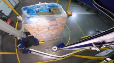 Kutu germe ambalaj makinesi. Palet ambalaj makinesi. Kutuları daire şeklinde plastik bir filme sarmak için bir makine. Plastik filmde kutular paketleniyor.