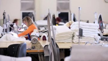 Birçok terzi bir giyim fabrikasında çalışır. Bir giyim fabrikasında çalışma süreci. Büyük dikiş atölyesi. Terziler fabrikada ürün yapar. Kumaş fabrikası