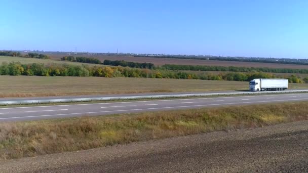 Bij zonnig weer rijdt er een witte wagen langs de snelweg. Vrachtwagen op de snelweg — Stockvideo