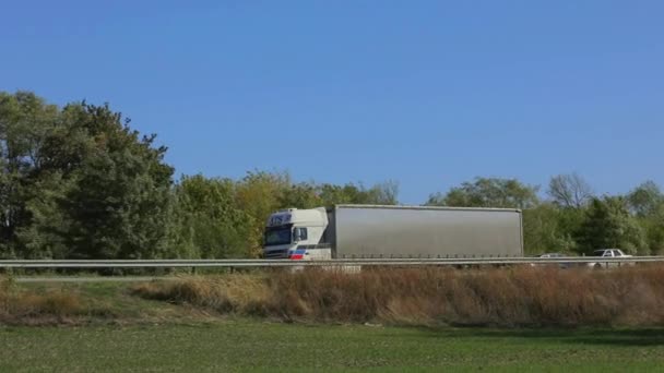 Teherszállítás. A teherautó egy modern úton halad. A teherautó az autópálya mentén halad napsütéses időben. Teherautó a pályán — Stock videók