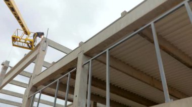 Asansördeki bir adam metal bir yapıya kaynak yapar. İnşaat alanında iş akışı. Metal kaynaklama