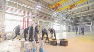 İşçi kovada boya karıştırıyor. Fıçıda boya karıştırmak, inşaat alanında kullanmak için malzeme hazırlamak..