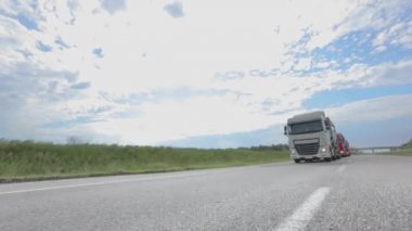Tankerli bir kamyon güneşli havada otoyola çıkıyor. Otoyol boyunca giden beyaz bir kamyon. Bir kamyon konvoyu otoban boyunca gidiyor.