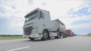 Otoyol boyunca giden beyaz bir kamyon. Tankerli bir kamyon güneşli havada otoyola çıkıyor. Bir kamyon konvoyu otoban boyunca gidiyor.