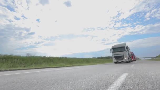 Ein Lastwagen mit Tankwagen fährt bei sonnigem Wetter über die Autobahn. Weiße Lastwagen fahren die Autobahn entlang. Ein Lastwagenkonvoi fährt über die Autobahn — Stockvideo