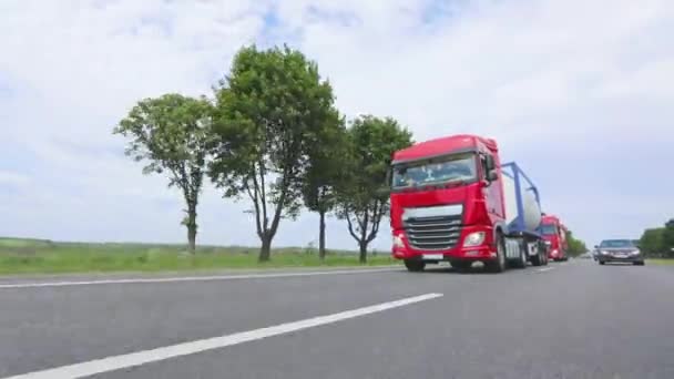 Eine Gruppe von Lastwagen fährt die Autobahn entlang. Ein LKW mit einem Tankwagen fährt auf die Autobahn. Moderne LKWs transportieren flüssige Fracht in Tanks. Der rote LKW fährt über die Autobahn. — Stockvideo