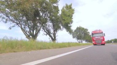 Kırmızı kamyon otoyol boyunca gidiyor. Bir grup kamyon otoyol boyunca gidiyor. Modern kamyonlar tanklarda sıvı kargo taşıyorlar