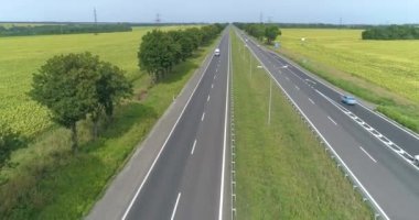 Araba manzaralı bir yol. Şehrin dışındaki otoyol, yolun kenarındaki tarlalar.