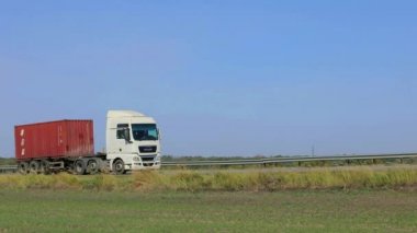 Nakliye aracı. Kamyon modern bir yolda gidiyor. Kamyon güneşli havada otoyol boyunca sürer. Pistte kamyon var