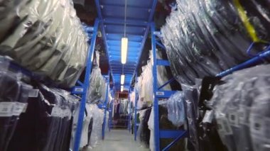 Giysiler depoda sıra sıra asılmış. Giysileri olan bir depo. Fabrikanın deposunda giysiler. endüstriyel iç