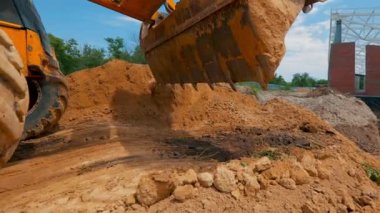 Bir traktör inşaat alanında çukur kazıyor. İnşaat alanında çalışma süreci. Traktör kovası yaklaş.