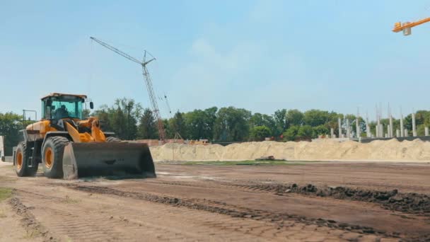 Moderner Traktor auf einer Baustelle. Großer gelber Traktor. Professionelle Baumaschinen. Arbeitsprozess auf der Baustelle — Stockvideo