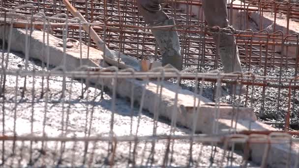 Pouring concrete to a metal structure. Workers make a reinforced concrete structure. Reinforced concrete. Working process at a construction site — Stockvideo