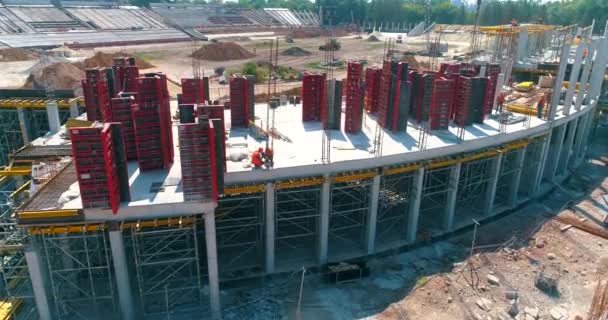 Modern bir futbol stadyumunun yapım süreci. İnşaatçılar yeni bir stadyumun şantiyesinde resmi işler yapıyorlar. Güçlendirilmiş beton yapının havadan görüntüsü — Stok video