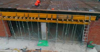 İnşaatçılar yeni bir stadyumun şantiyesinde resmi işler yapıyorlar. Modern bir futbol stadyumunun yapım süreci. Güçlendirilmiş beton yapının havadan görüntüsü