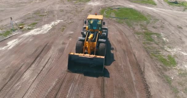 Moderner Traktor auf einer Baustelle aus der Luft. Großer gelber Traktor. Professionelle Baumaschinen. Arbeitsprozess auf der Baustelle — Stockvideo