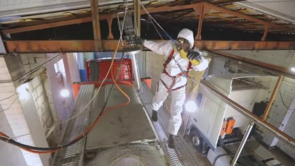 Kimyasal koruma bölümünde çalışan bir işçi bir kamyon tankının kapağını açıyor. Temizlik istasyonunda koruyucu takım elbiseli bir işçi. İşçi zararlı kimyasallarla çalışır. — Stok video