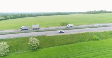 Yeşil tarlanın yakınındaki yolda giden bir kamyon. Kamyon otoyolda gidiyor. Kamyon otoban manzarası boyunca gidiyor.